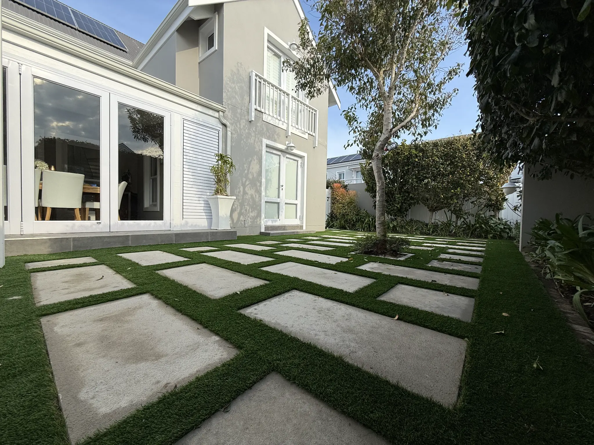 Stepping-stone paving set into artificial grass beside a residential home