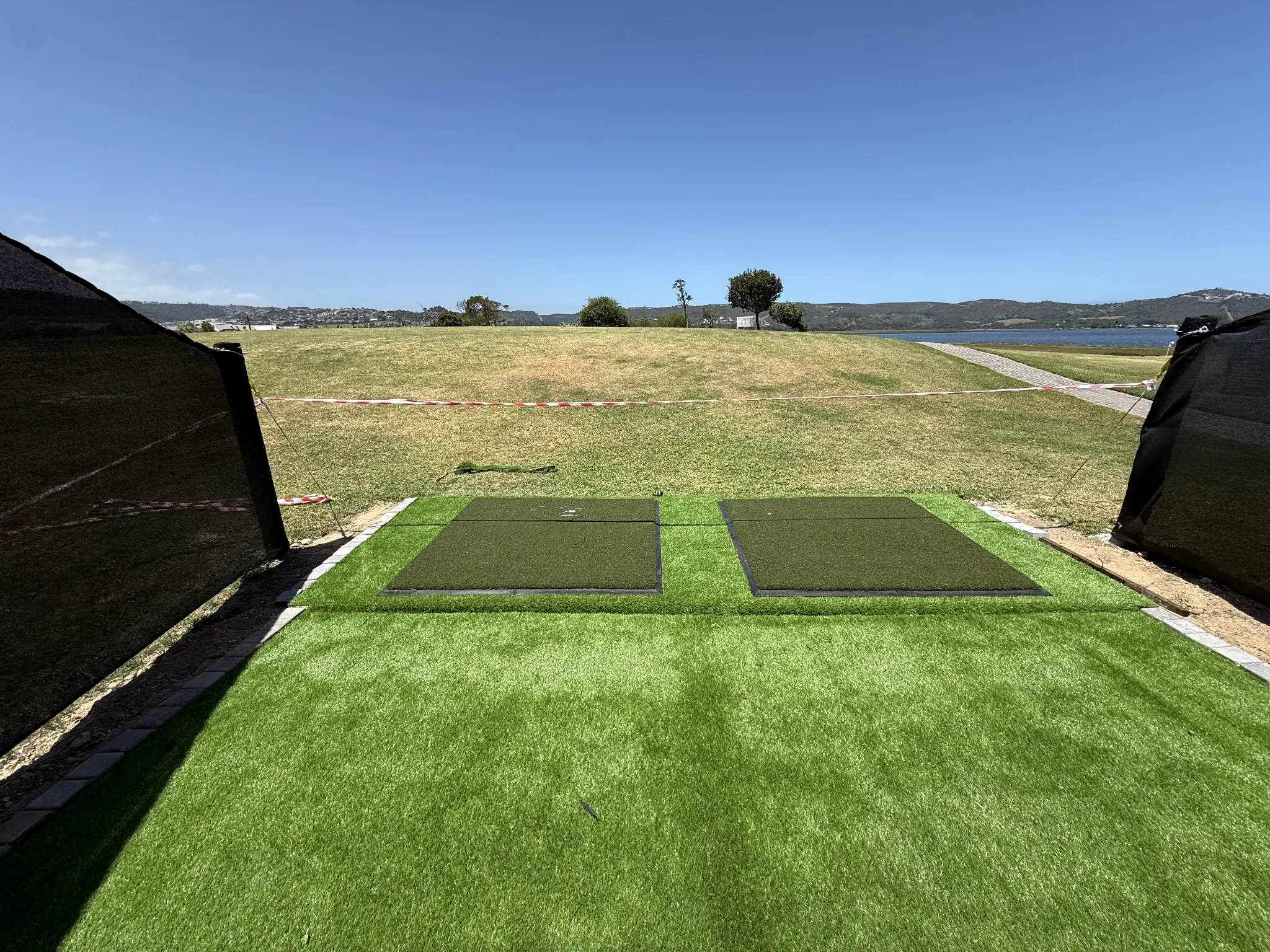 Artificial grass golf tee area overlooking a coastal landscape
