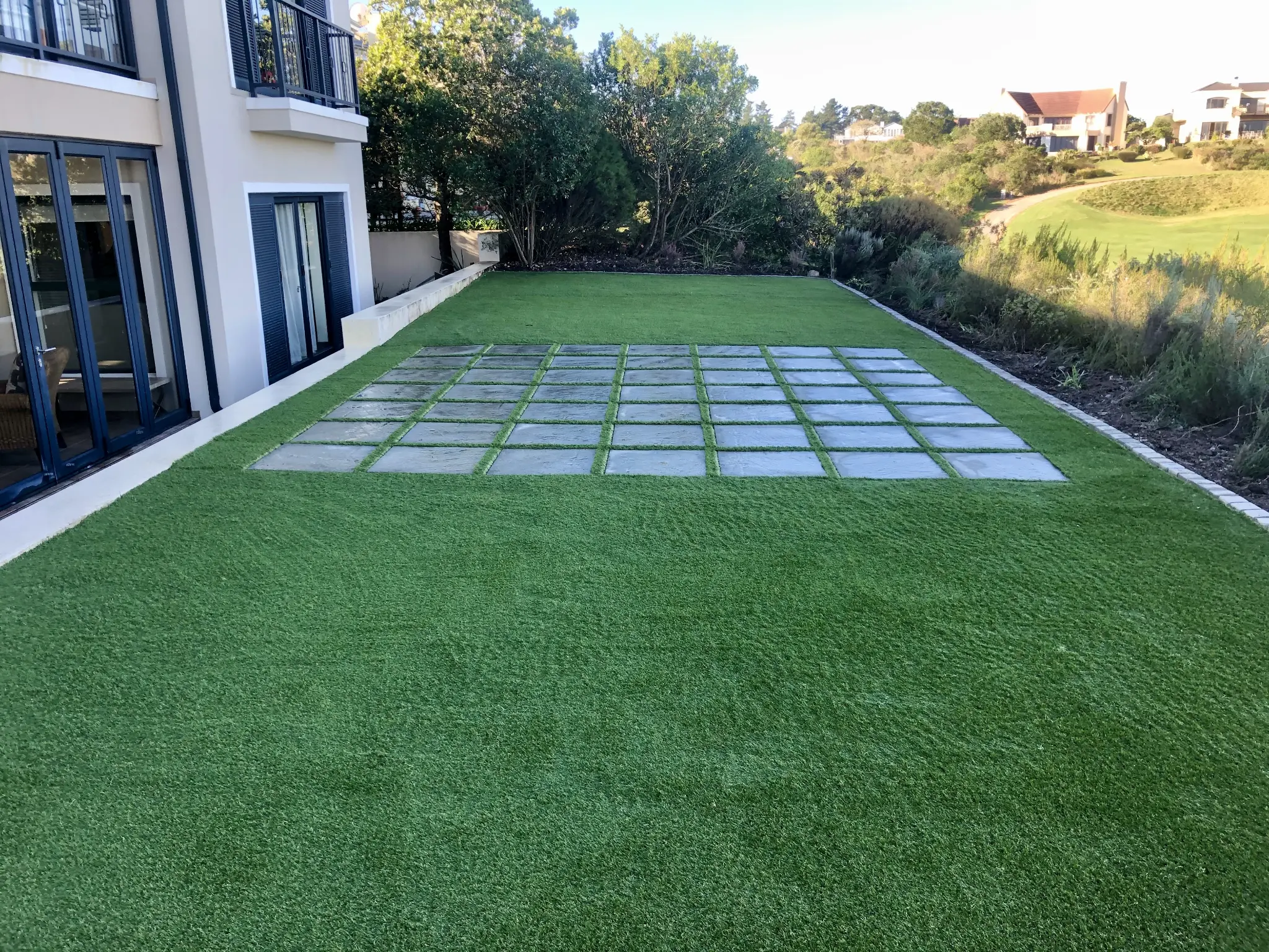 Artificial grass lawn terrace with a grid of square stepping stones